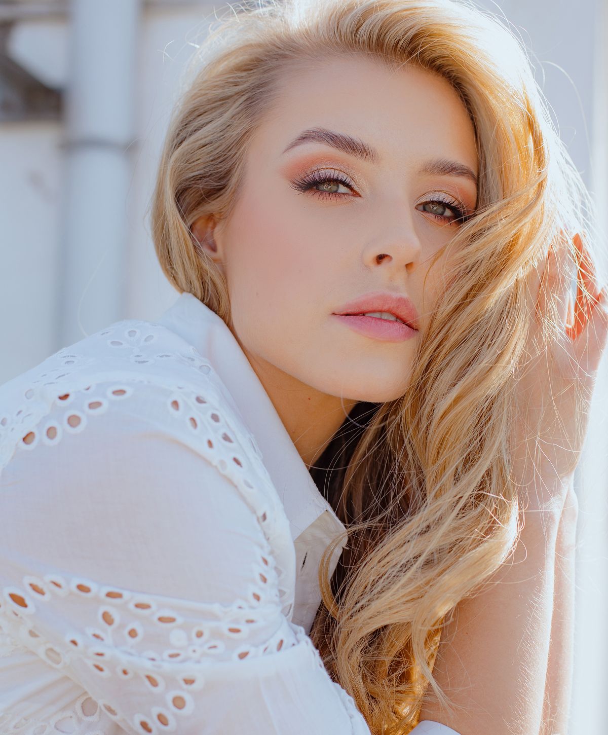 Blonde woman with soft makeup and shirt.
