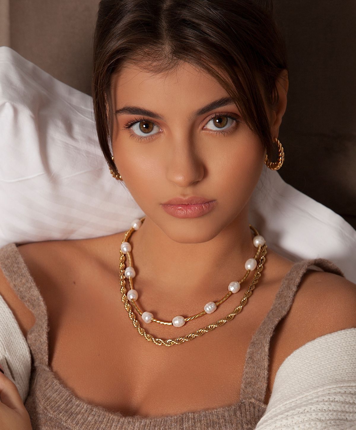 Young woman with layered pearl and gold necklaces.