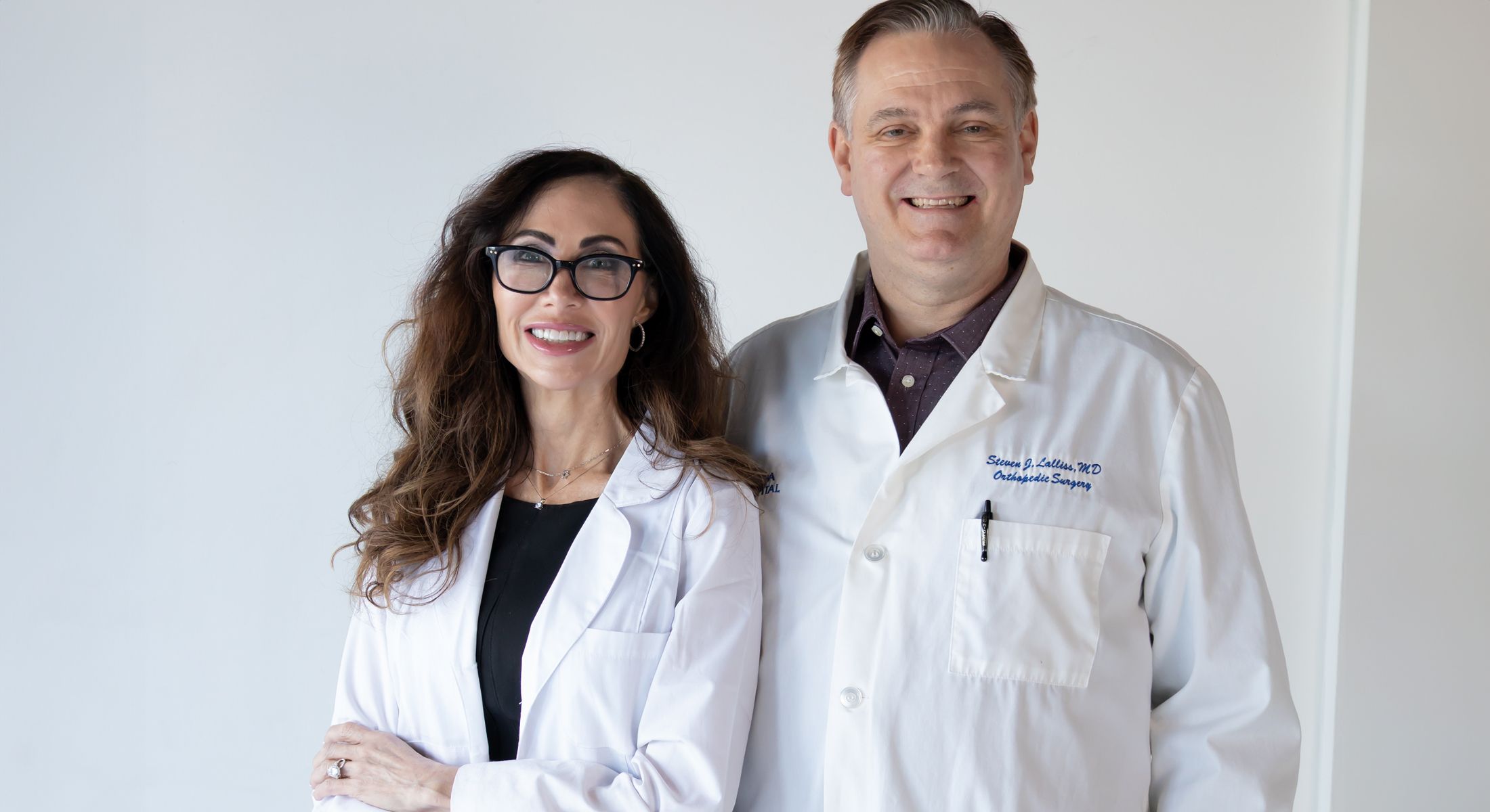 Two smiling doctors in white lab coats.