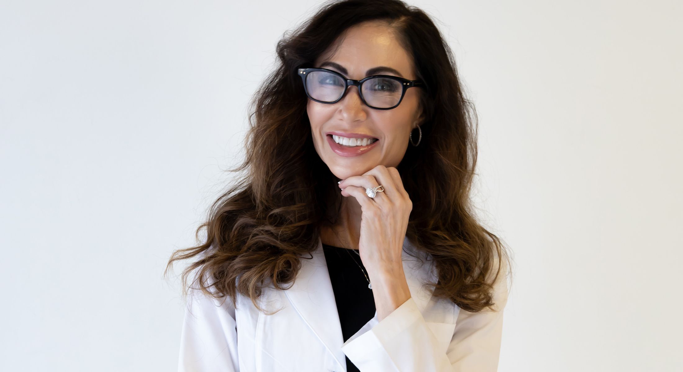 Smiling woman in lab coat with glasses.