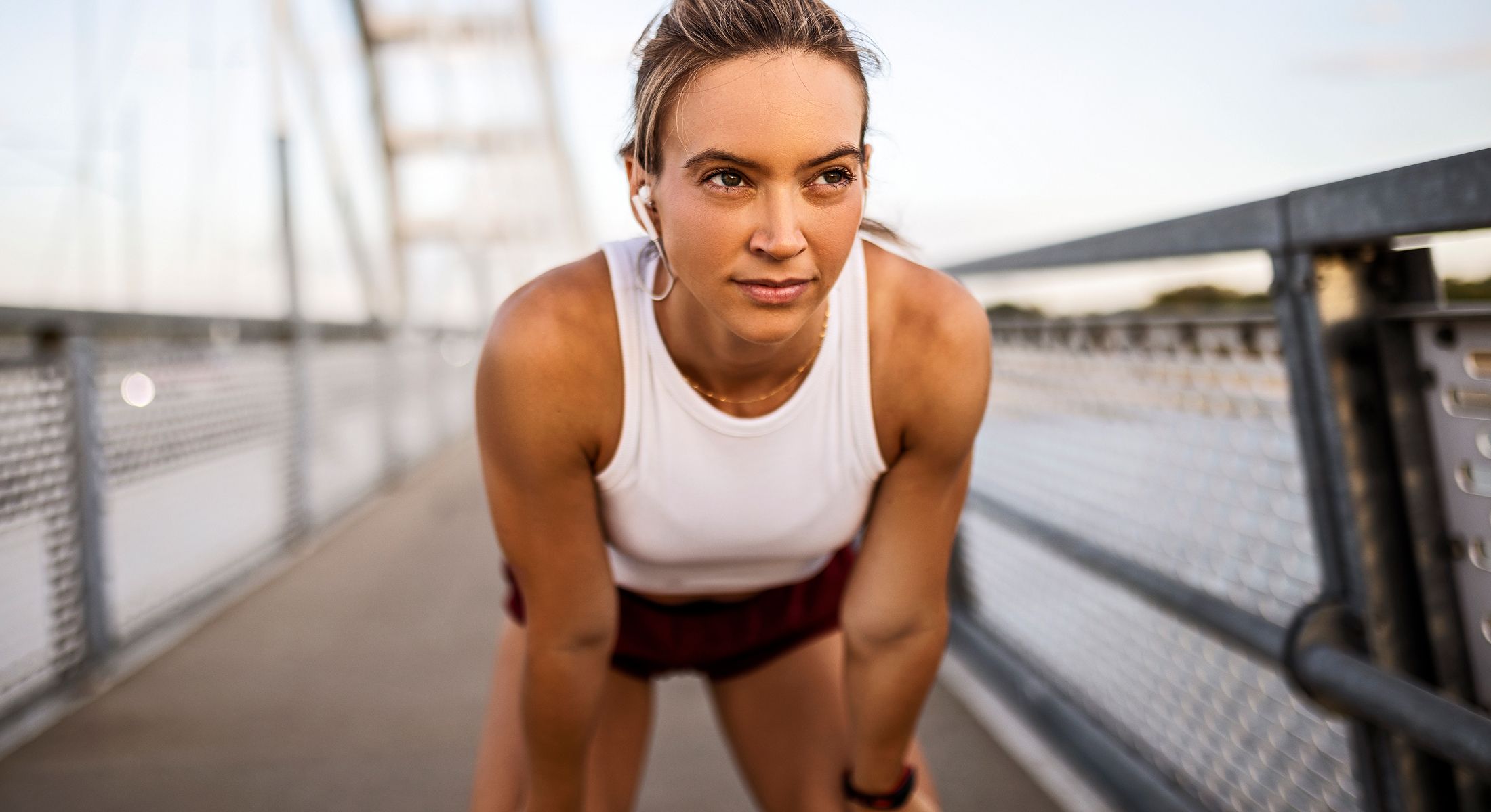 Athlete resting on bridge with earbuds in.