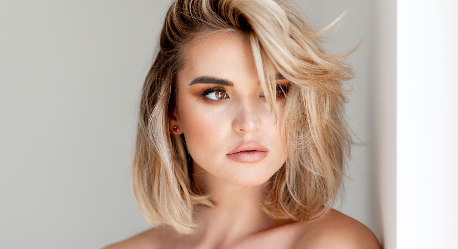 Woman with stylish blonde bob hairstyle and makeup.