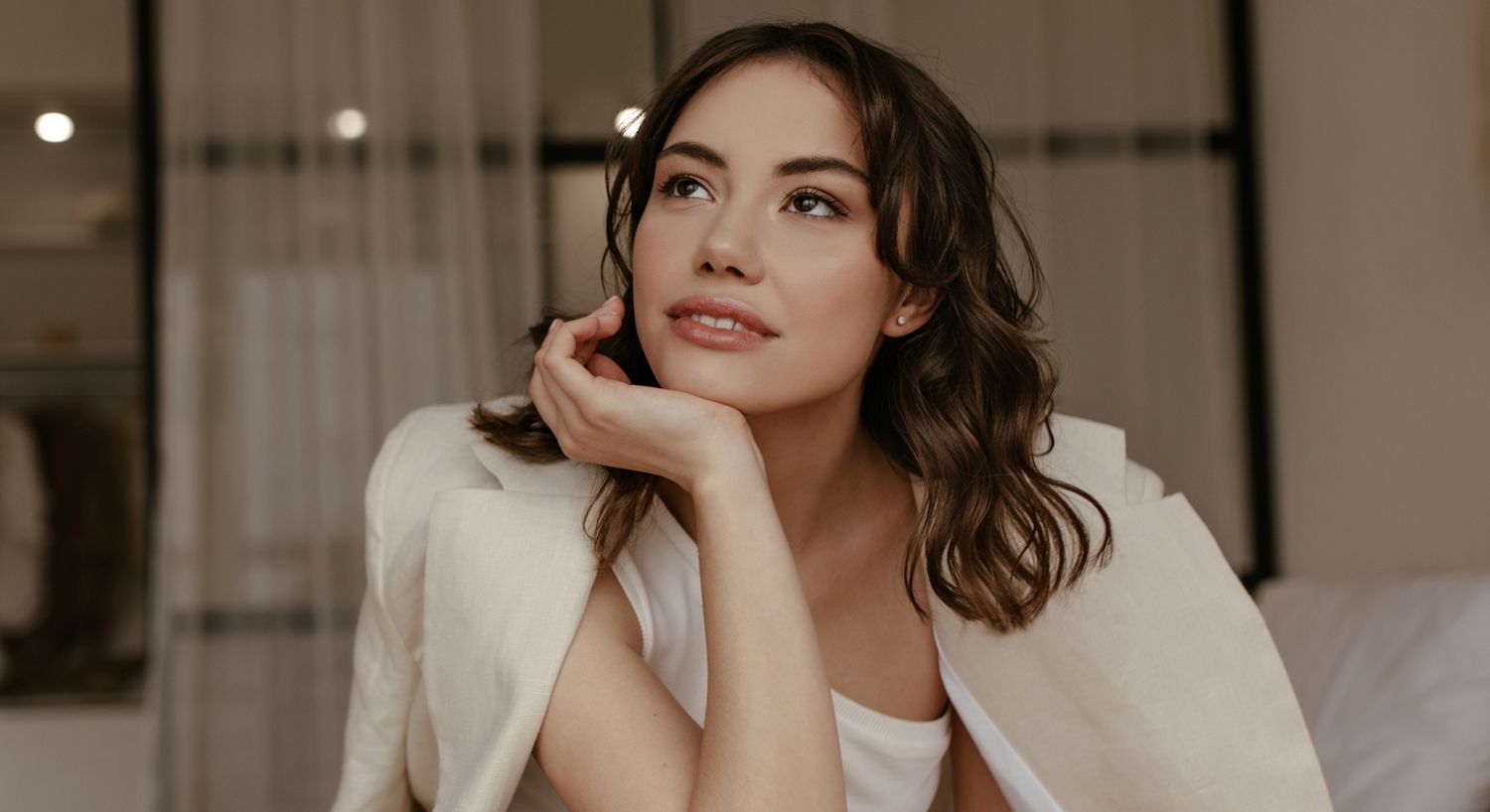 Woman in thoughtful pose, soft indoor lighting.